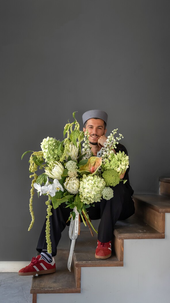 Three white proteas with green hydrangeas and white orchids