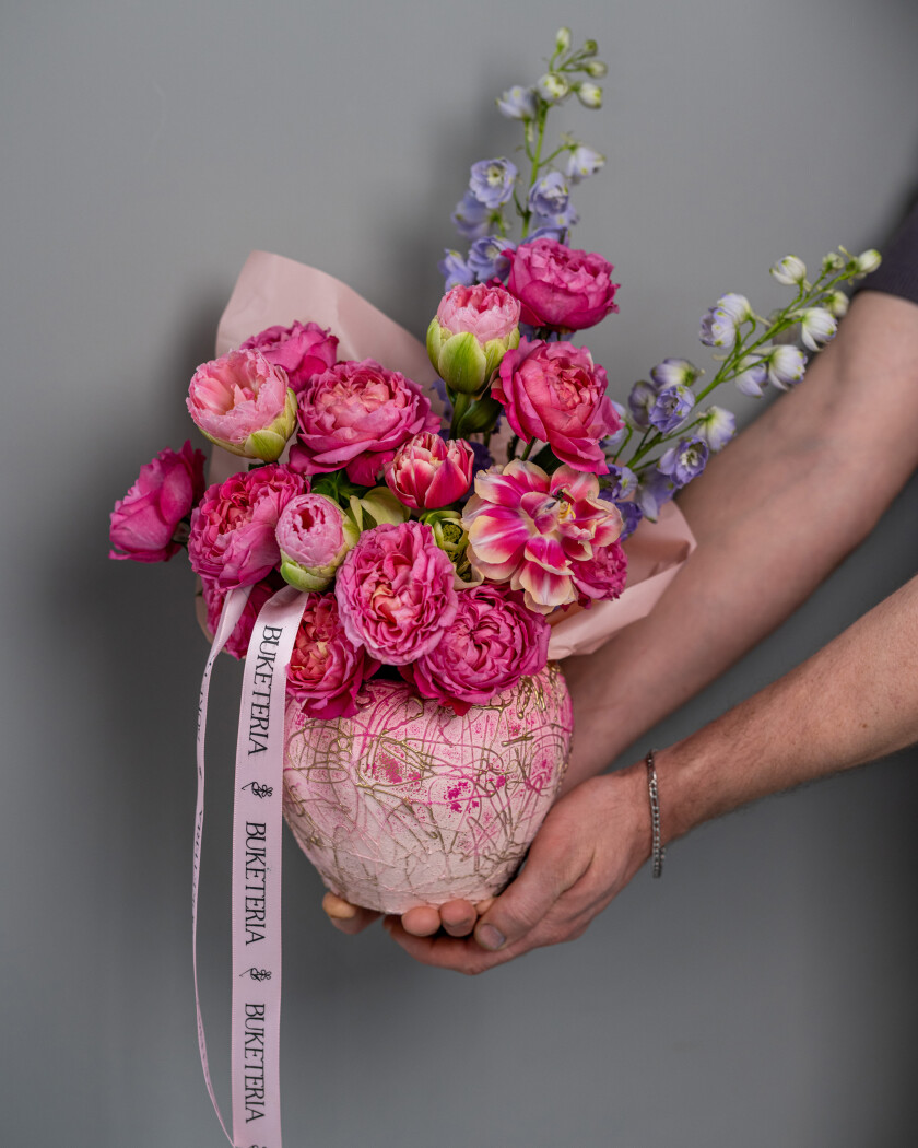Decorative arrangement of blush spray roses and light blue delphiniums