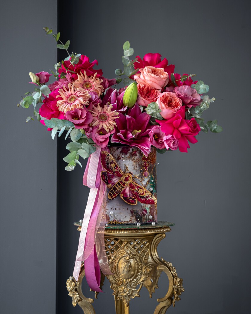 Decorative composition of hot pink garden roses and peach gerberas in an art box