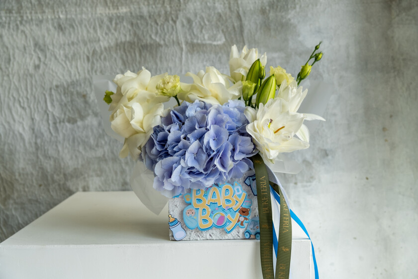 Decorative composition of white roses and blue hydrangeas in an art box