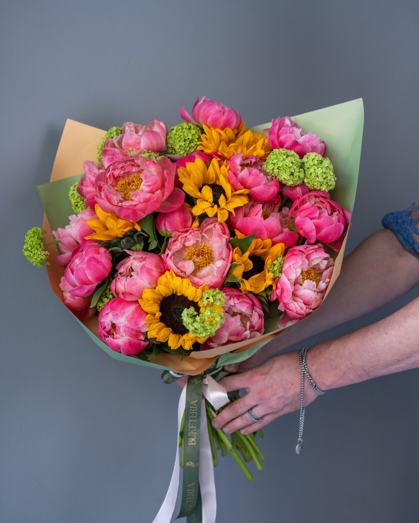 Pink peonies with yellow sunflowers and green viburnum