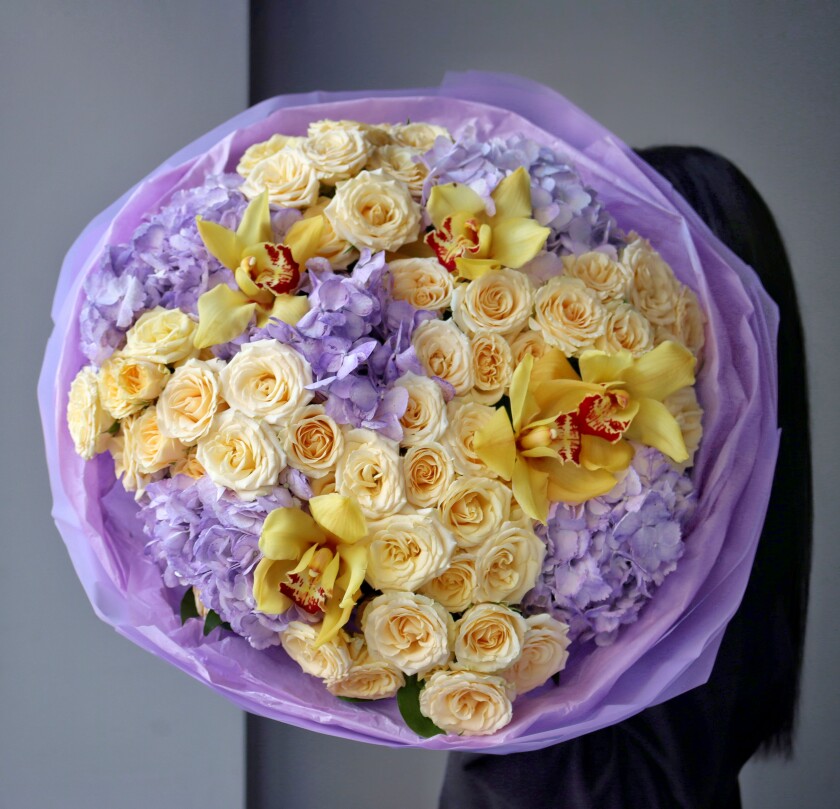Peach spray roses with light blue hydrangeas and yellow cymbidium orchids