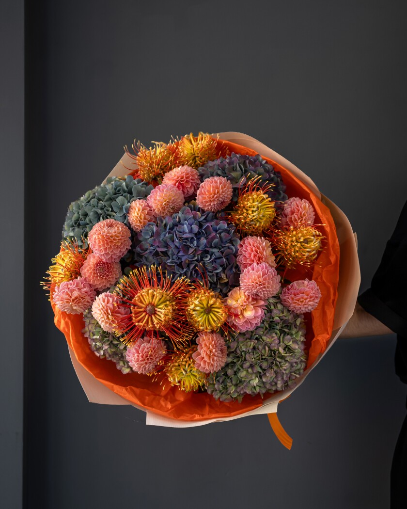 Peach dahlias with light blue hydrangeas and orange leucospermum
