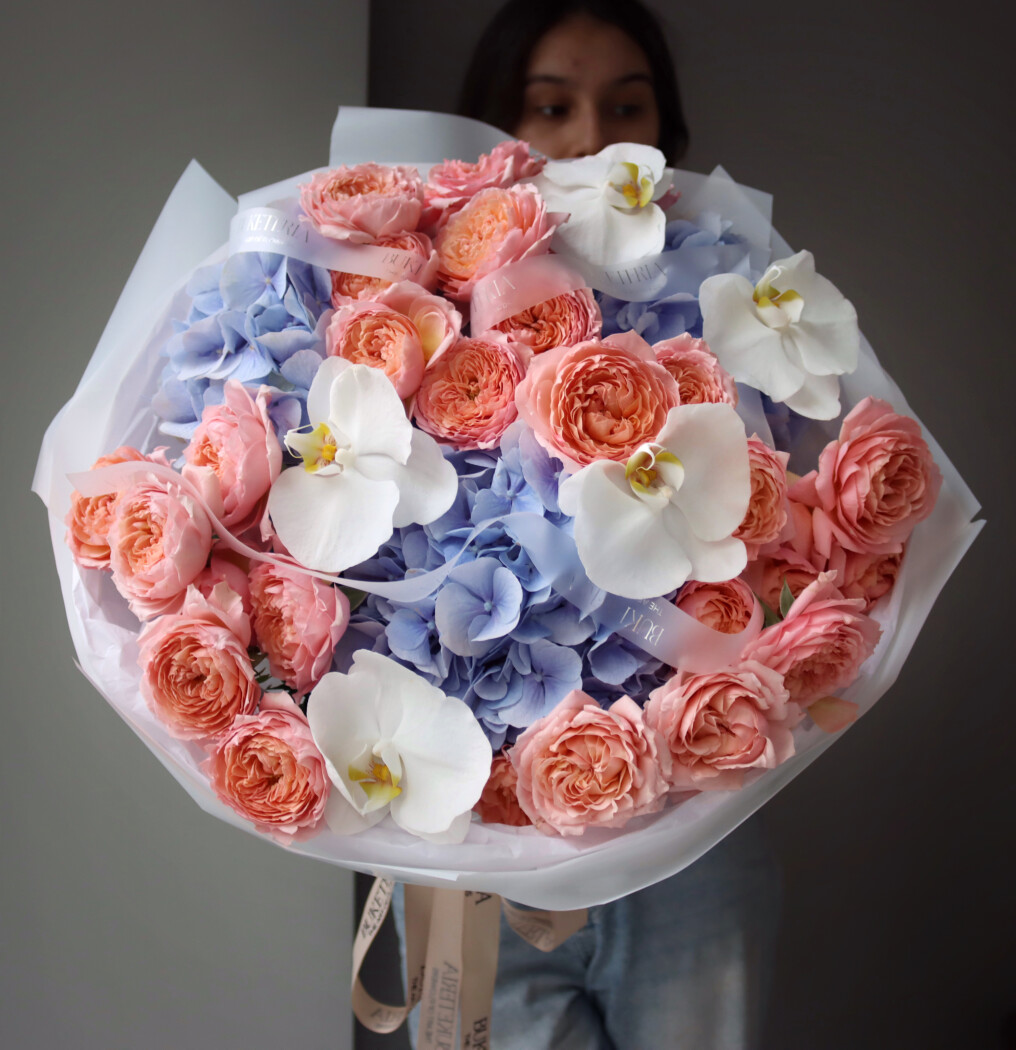 Peach garden roses with blue hydrangeas and white orchids