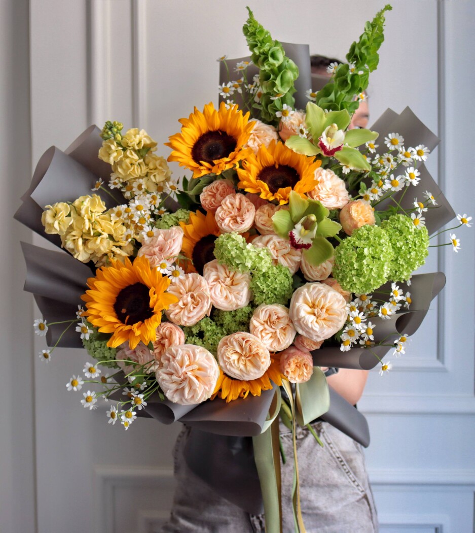 Peach spray roses with yellow sunflowers and green viburnum