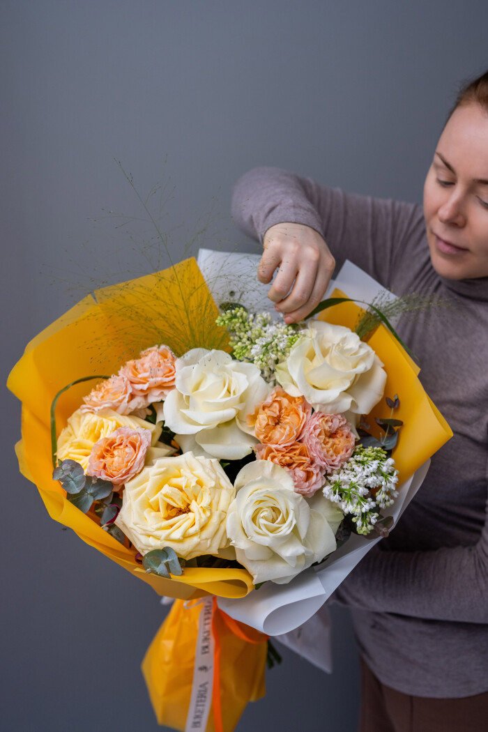 Three cream and light yellow hybrid tea roses with pink lilacs and peach spray roses