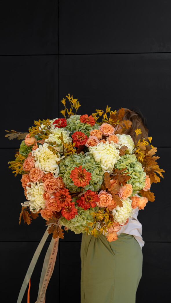 Orange pompon chrysanthemums with apricot garden roses and green hydrangeas
