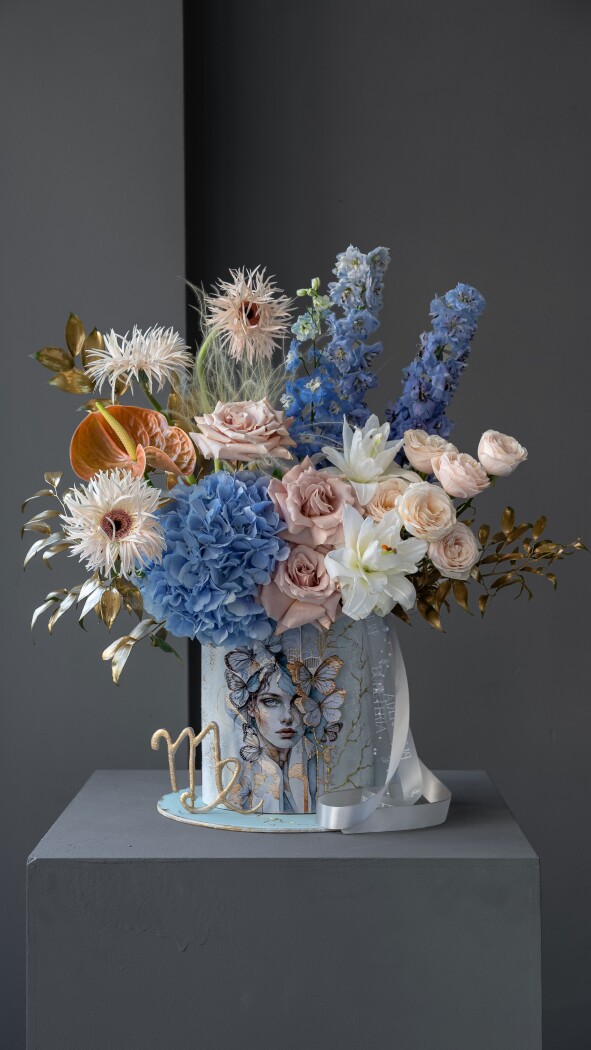 Decorative composition of blue delphiniums and blush gerberas