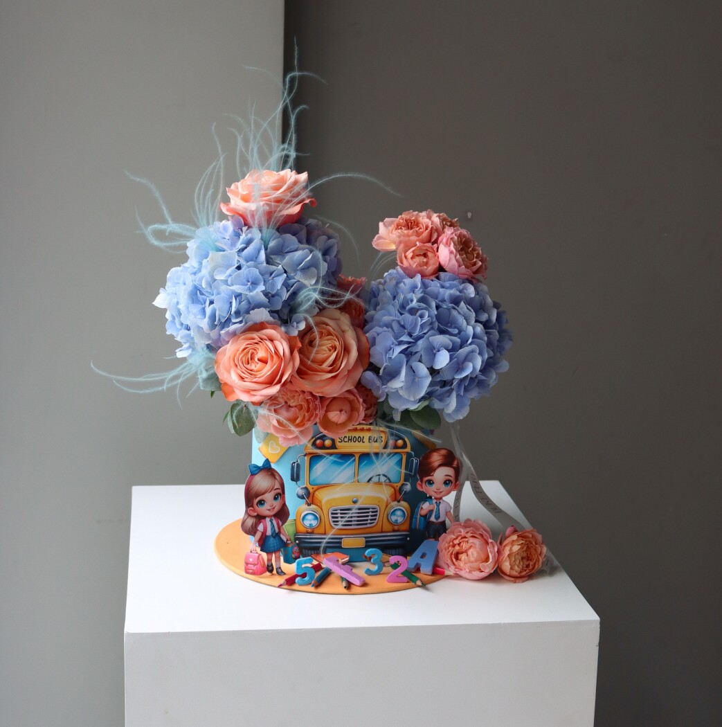 Decorative composition of peach spray roses and blue hydrangeas in an art box