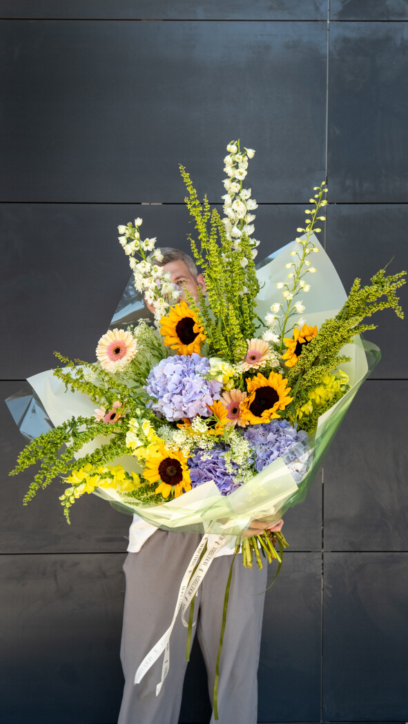 Three blue hydrangeas with yellow sunflowers and peach gerberas