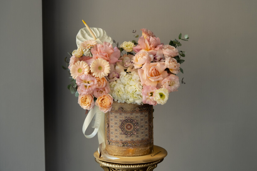 Decorative composition of peach garden roses and white hydrangeas in an art box
