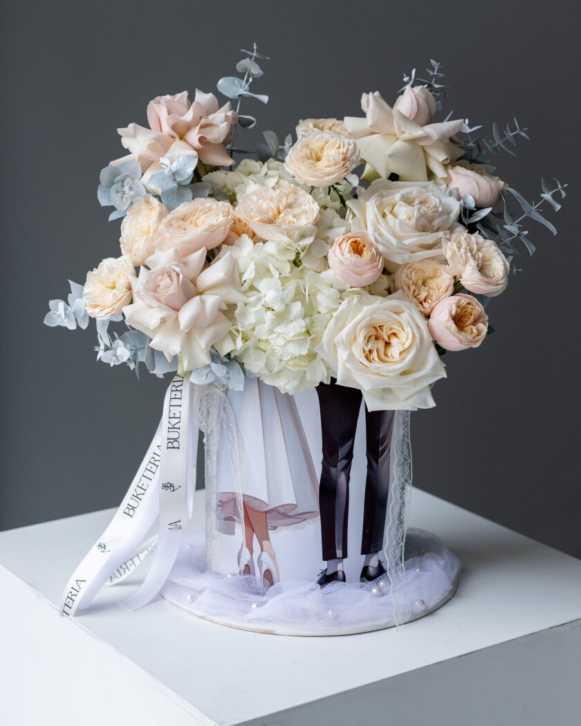 Decorative composition of blush spray roses and cream garden roses in an art box