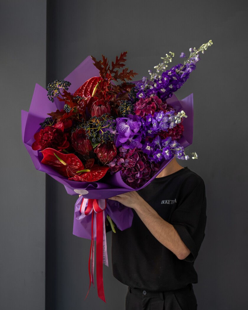 Three dark red proteas with lilac delphiniums and red anthuriums