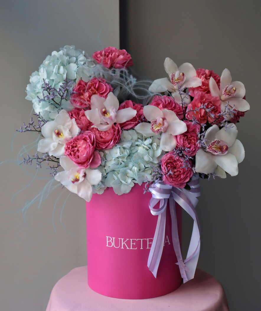 Decorative composition of white cymbidium orchids and light blue hydrangeas