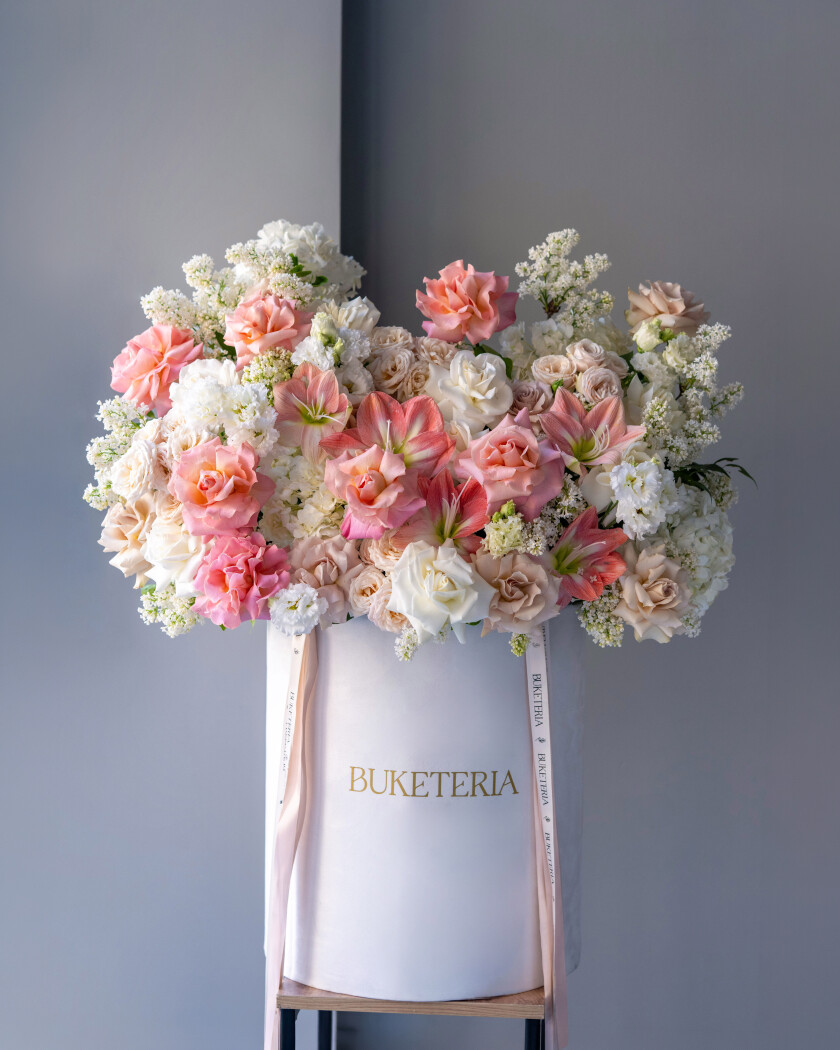 Decorative composition of blush garden roses and white hydrangeas in an art box