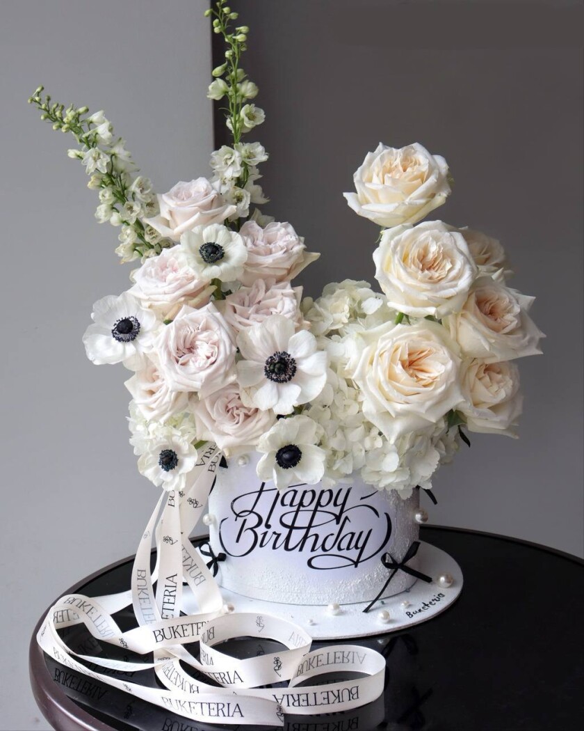 Decorative composition of blush garden roses and white anemones in an art box