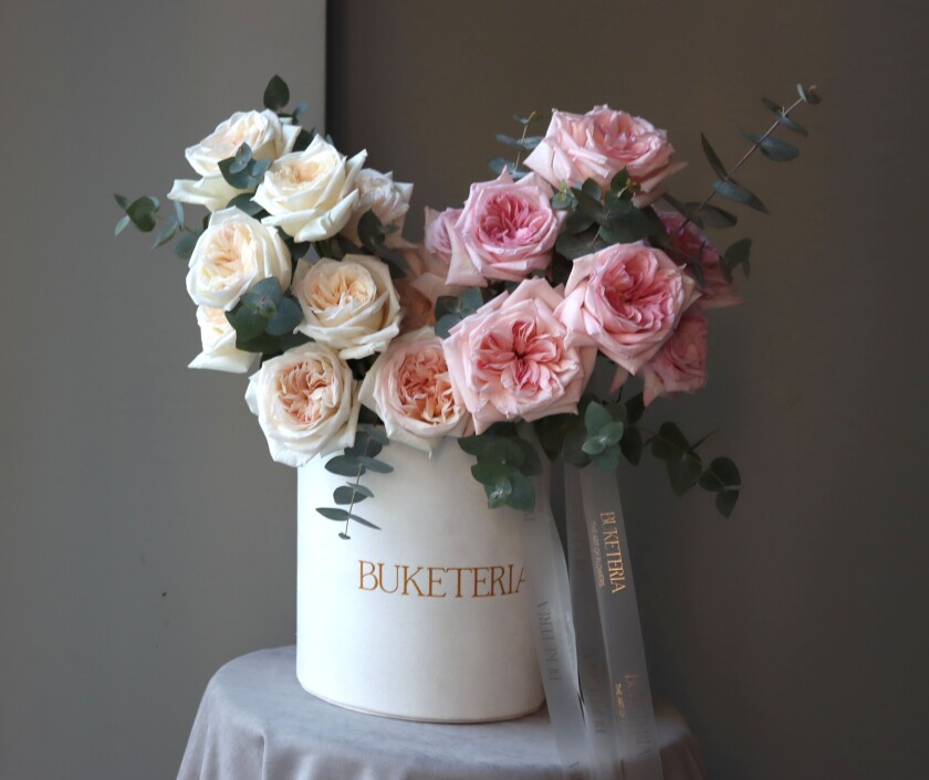 Decorative composition of cream and dusty pink garden roses in a box