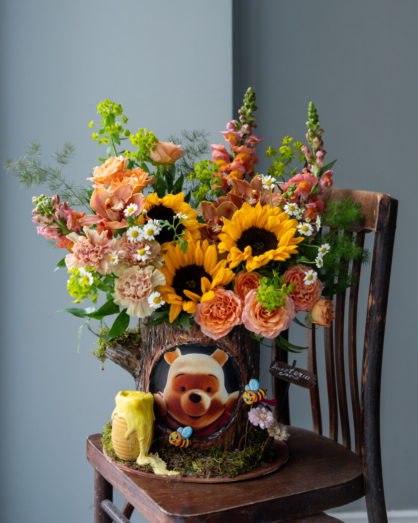 Three sunflowers with peach garden roses and cymbidium orchids