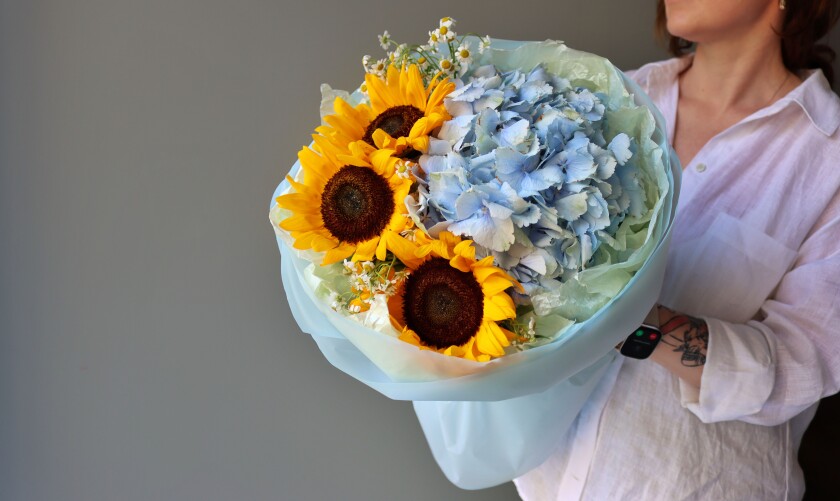 Three yellow sunflowers and one light blue hydrangea