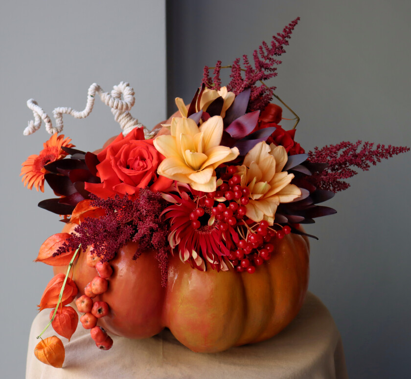Red hybrid tea roses with peach lilies and burgundy leucadendron