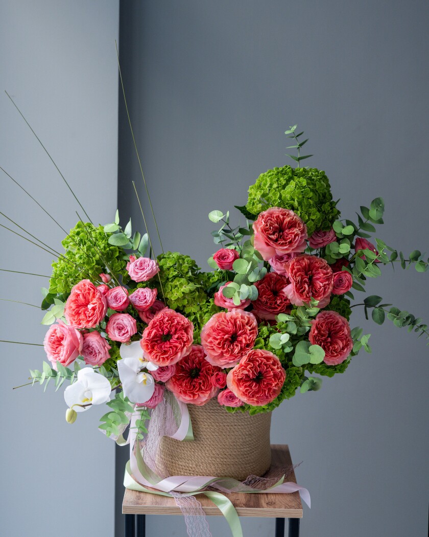 Decorative arrangement of green hydrangeas, white orchids, and coral garden roses