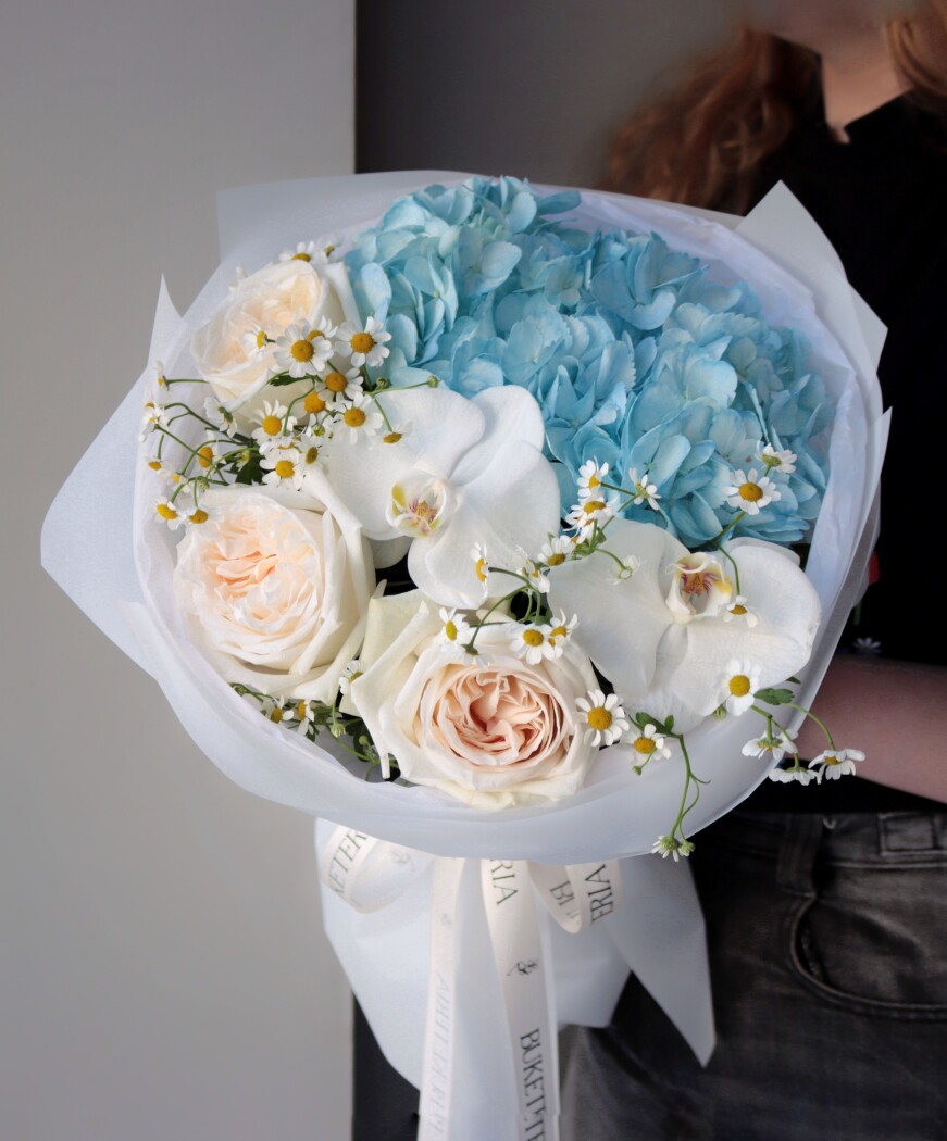 Peach garden roses with light blue hydrangea and white orchids