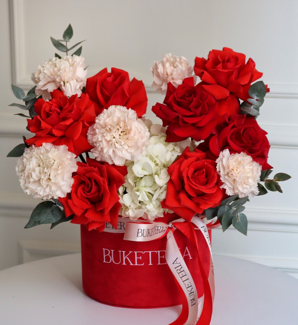 Decorative composition of red hybrid tea roses, cream carnations, and white hydrangea