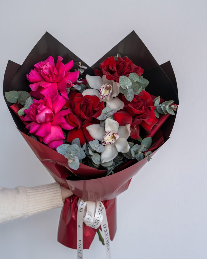 Three hot pink hybrid tea roses with red garden roses and white cymbidium orchids