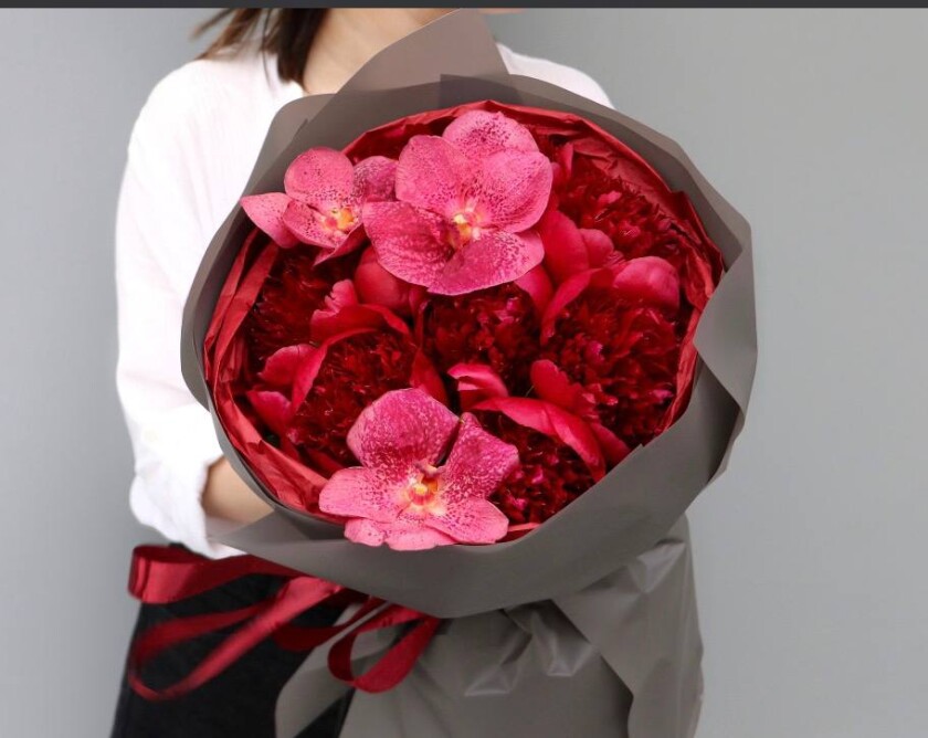 Red peonies and red vanda orchids in a luxurious bouquet
