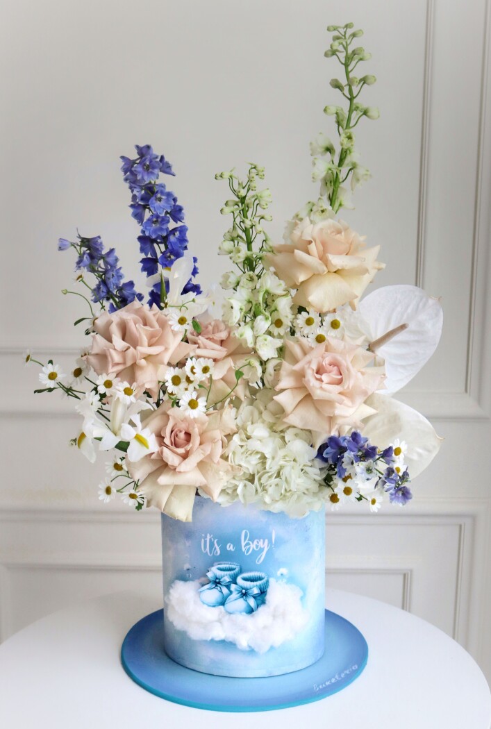 Decorative composition of blue delphiniums and peach garden roses in an art box