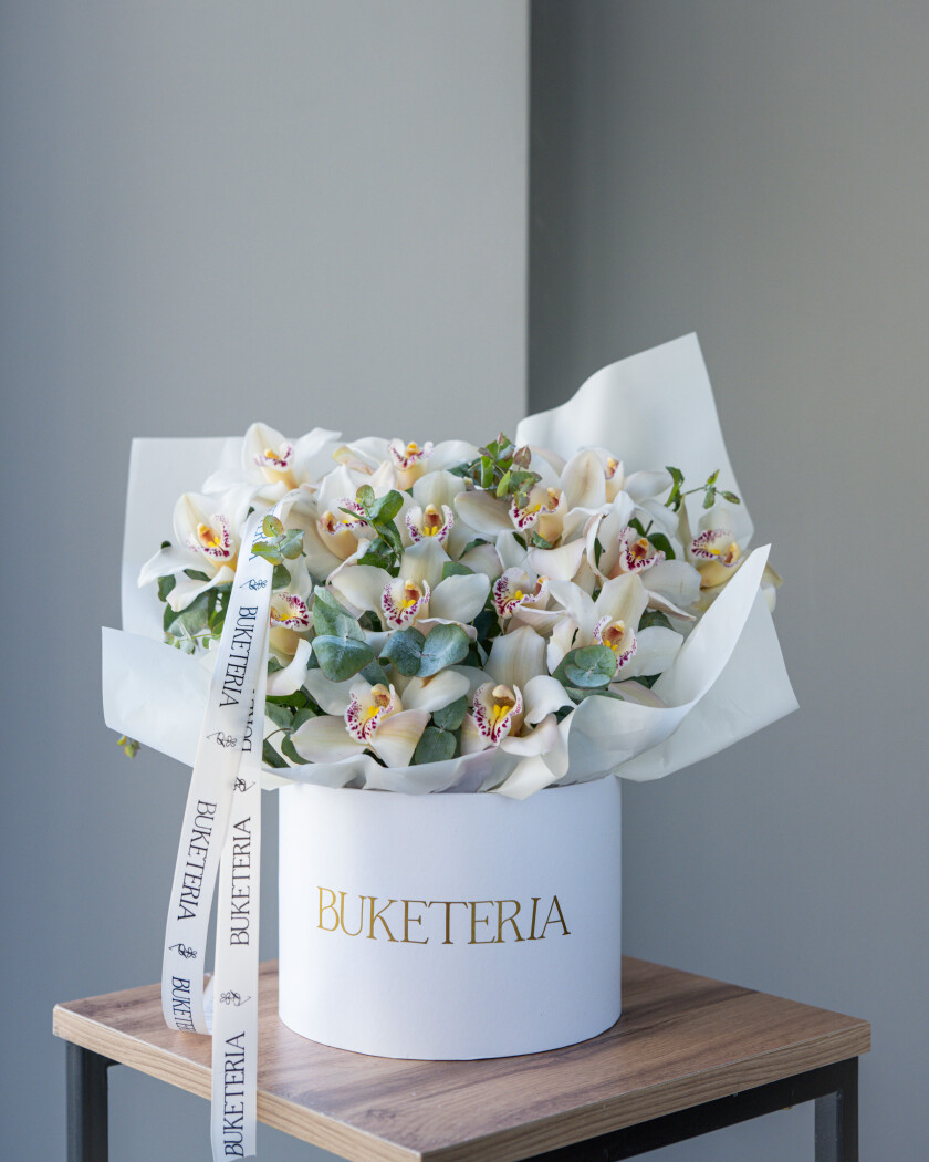 Decorative composition of white cymbidium orchids in a luxury box