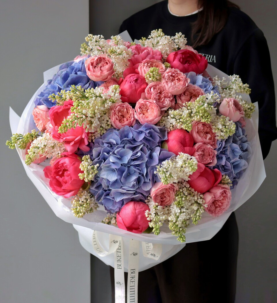 Seven coral peonies with blue hydrangeas and dusty pink spray roses