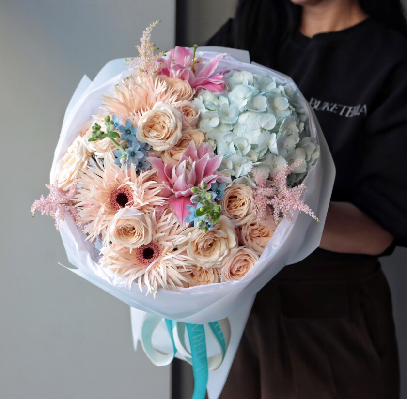 Peach spray roses with blush gerberas and blue hydrangeas