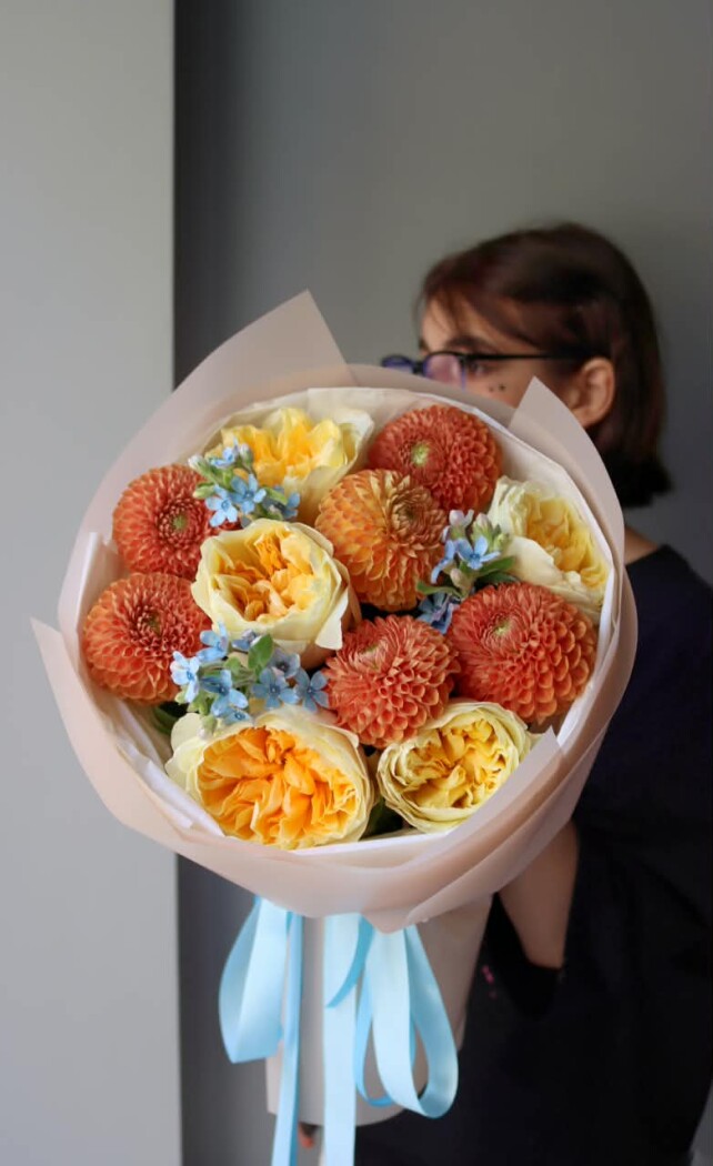 Light blue tweedia with peach roses and orange dahlias