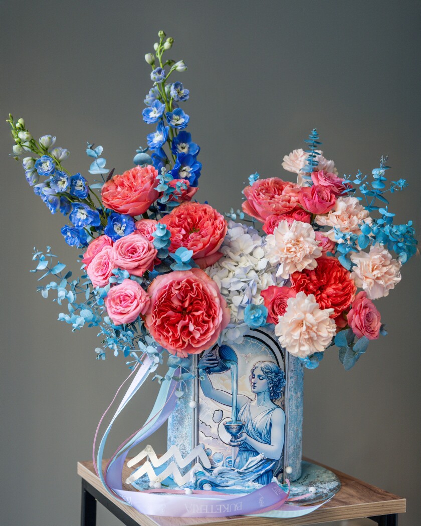 Decorative composition of coral garden roses with blue delphiniums