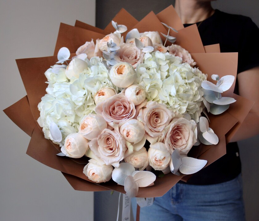 Eight blush garden roses with six peach spray roses and white hydrangeas