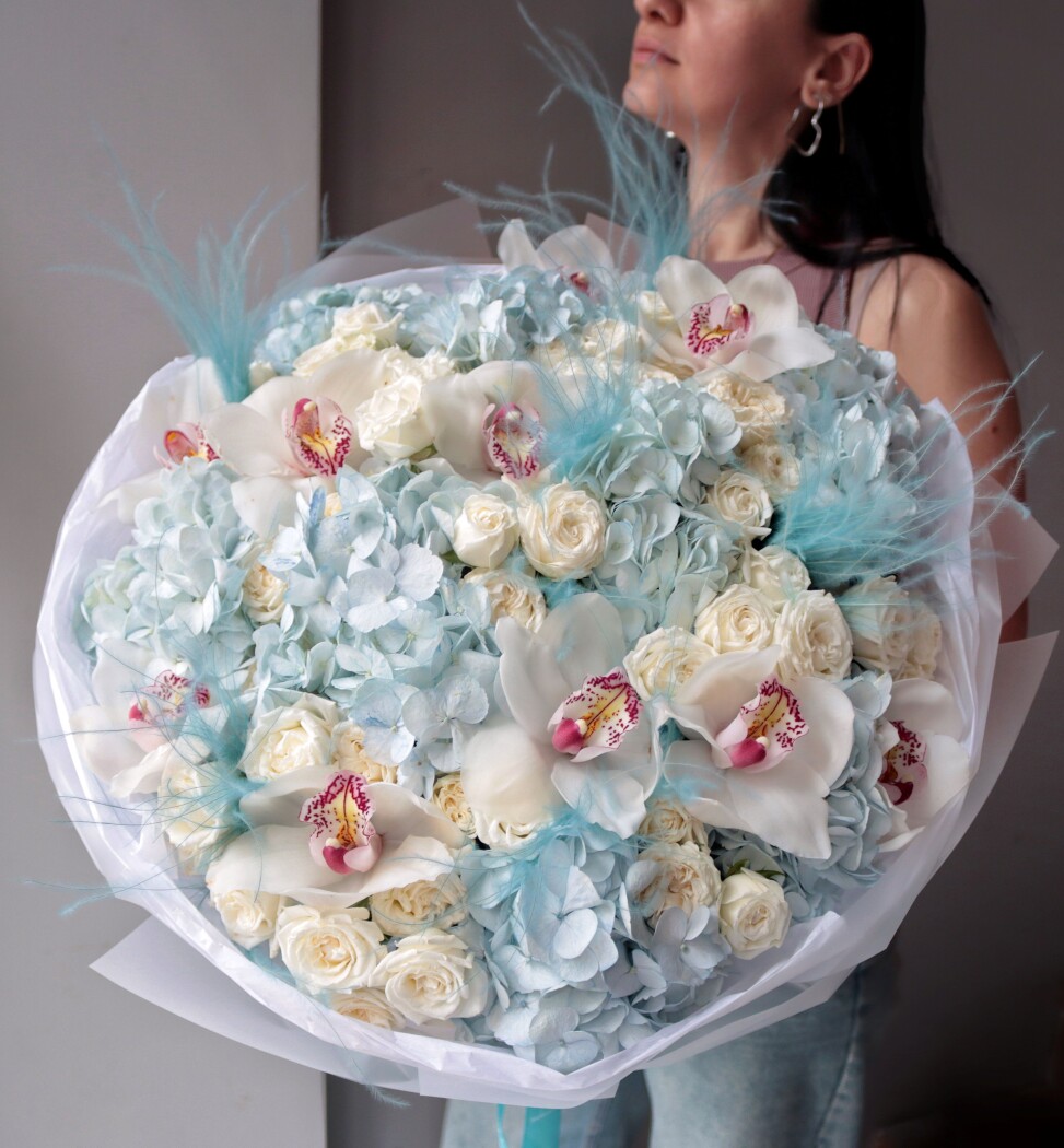 Light blue hydrangeas with cream spray roses and white cymbidium orchids