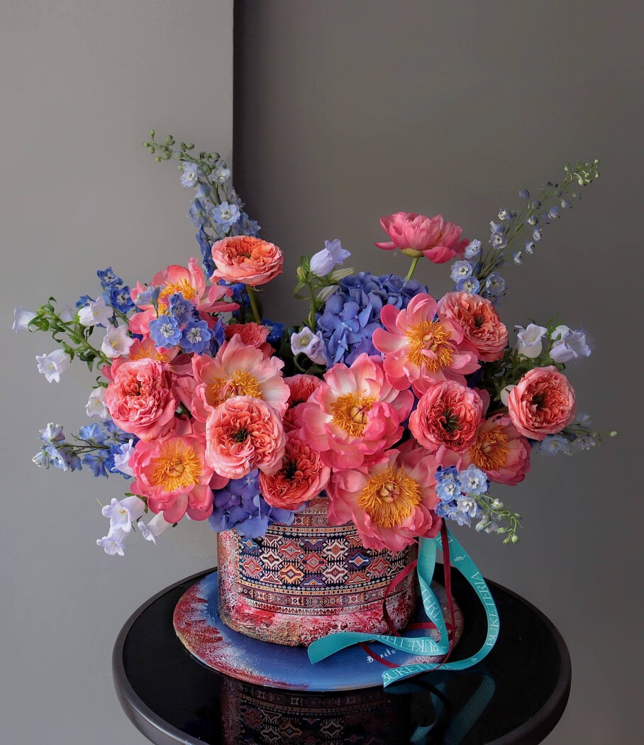 Nine pink peonies with coral garden roses and light blue delphiniums