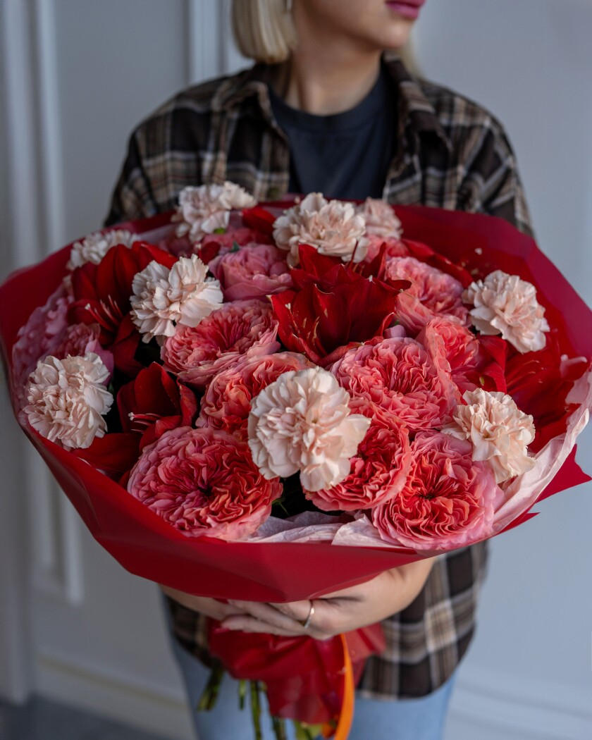 Seventeen dusty pink garden roses with red amaryllis and peach carnations