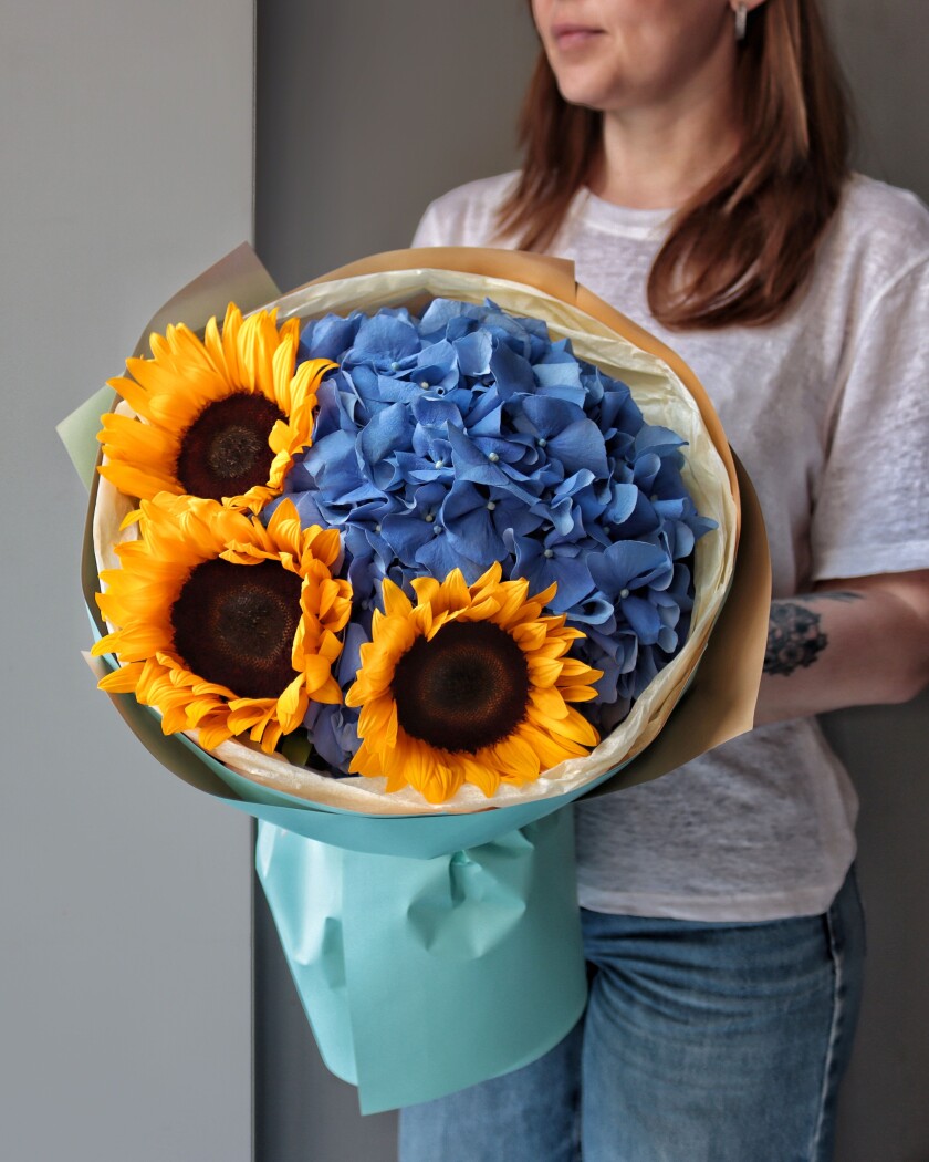 Three yellow sunflowers with blue hydrangea