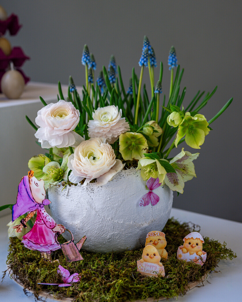Decorative arrangement of white ranunculus, blue muscari, and green hellebores
