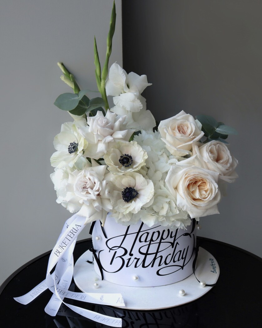 Decorative composition of cream garden roses and white anemones in an art box