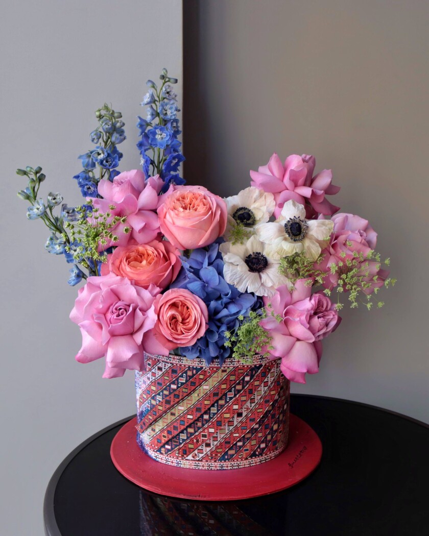 Decorative composition of peach garden roses and blue delphiniums in an art box