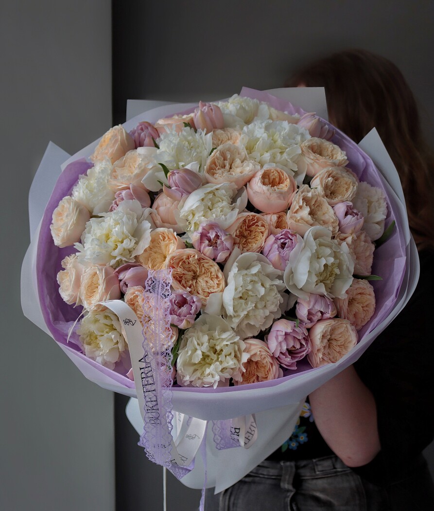 Spring bouquet of white peonies, peach spray roses, and mauve tulips