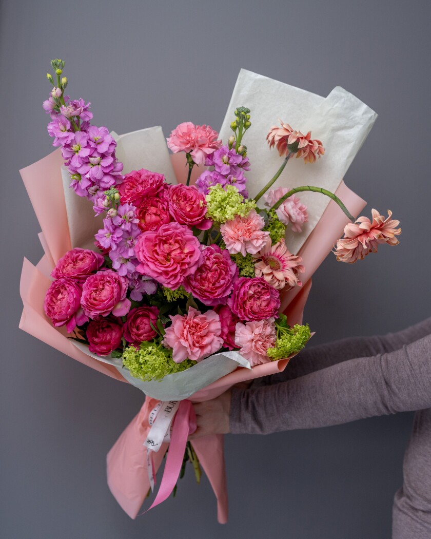 Three peach spray roses with green viburnum and hot pink gerberas