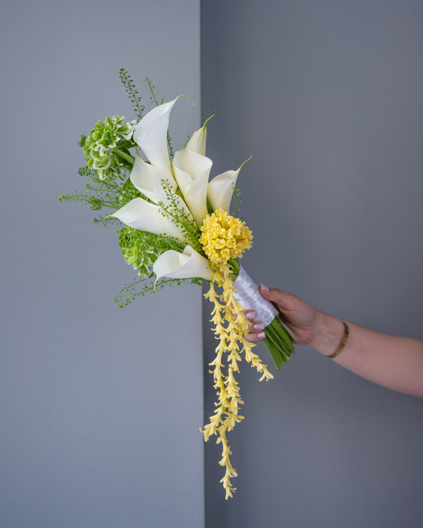 Elegant bouquet of white callas, cream ranunculus, and yellow hyacinths